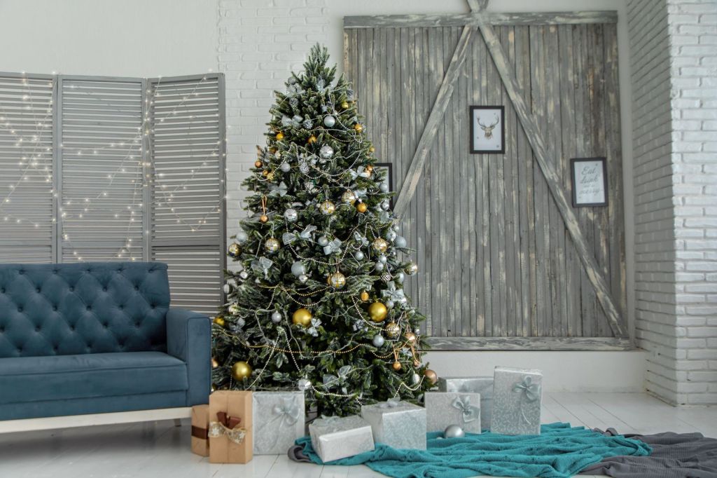 Christmas tree with wrapped gift boxes beside a sofa in a cozy living room