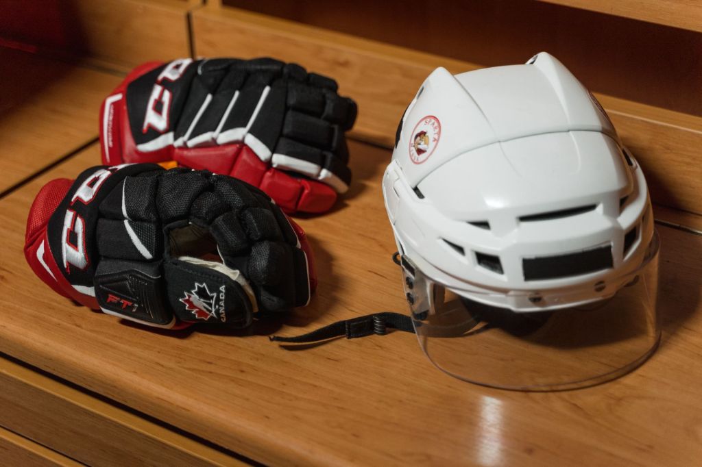 Hockey helmet and gloves resting on a wooden bench